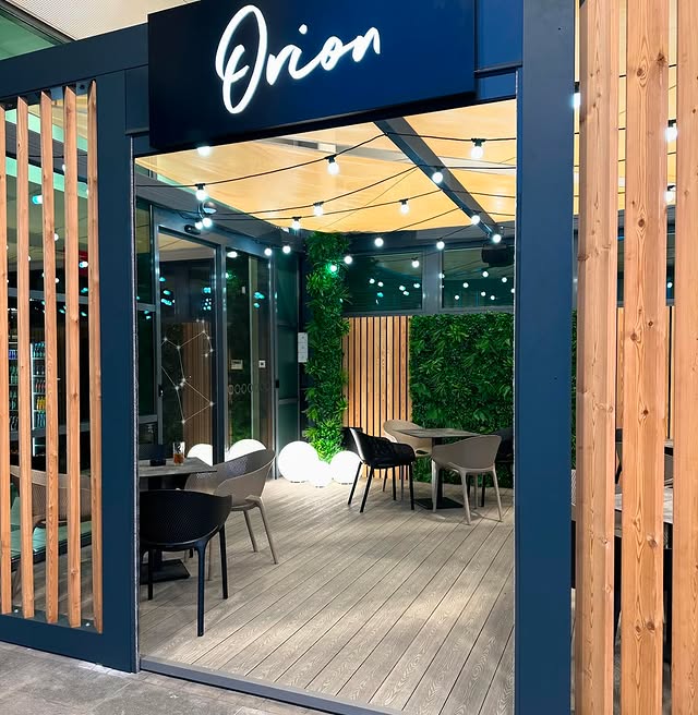 Vhod v Kavarno Orion s svetlečim napisom ponoči